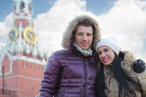 Young man and woman stand near Spasskaya tower on Red Square