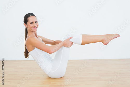 Toned woman doing the boat pose in fitness studio