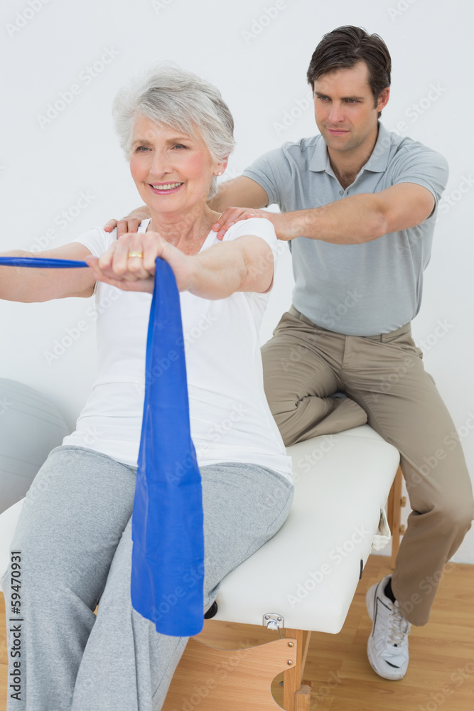 Fototapeta premium Male therapist assisting senior woman with exercises