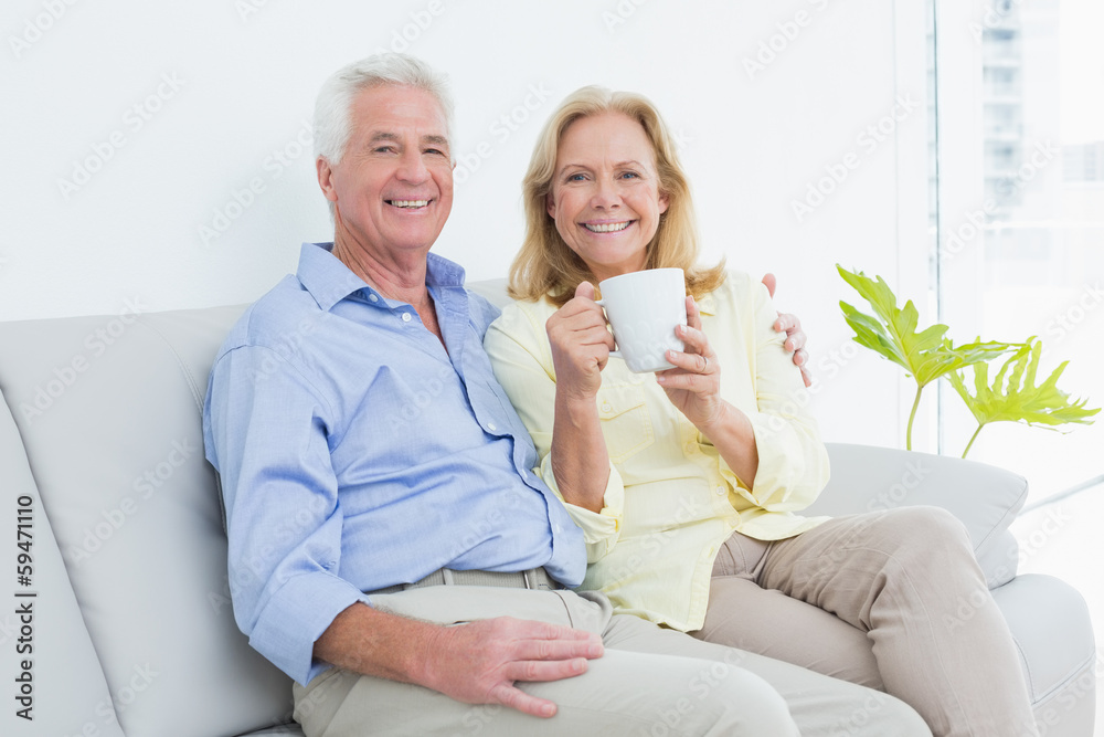 Senior couple with coffee cup sitting on sofa Senior couple with coffee cup sitting on sofa