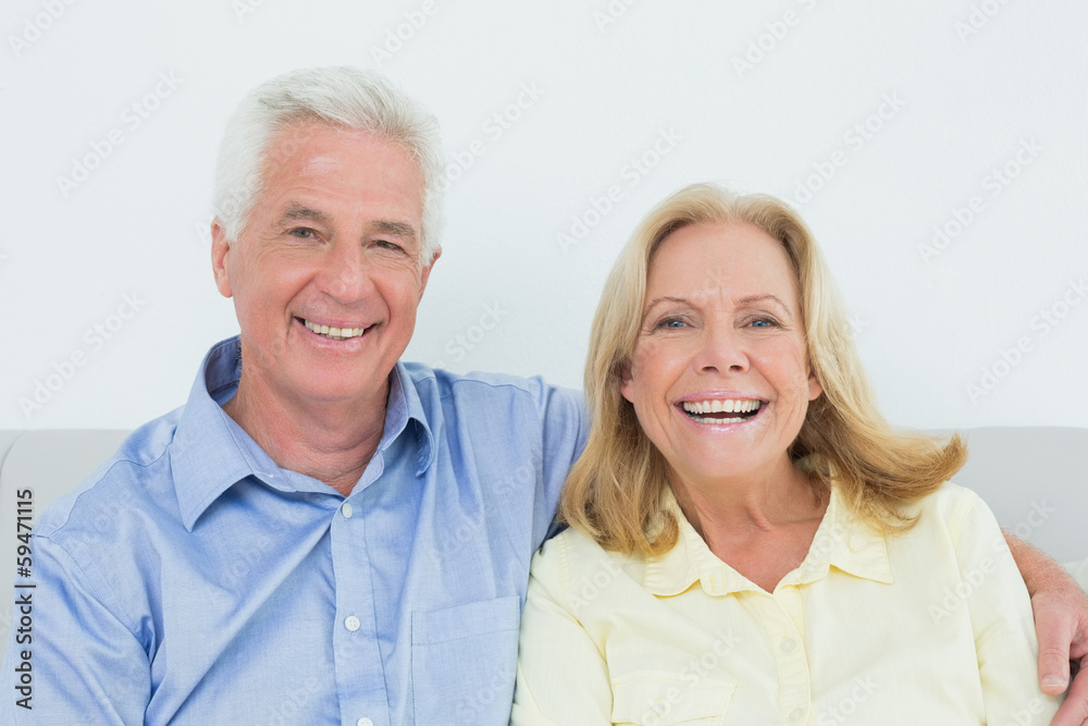 Cheerful loving senior couple sitting on sofa Cheerful loving senior couple sitting on sofa