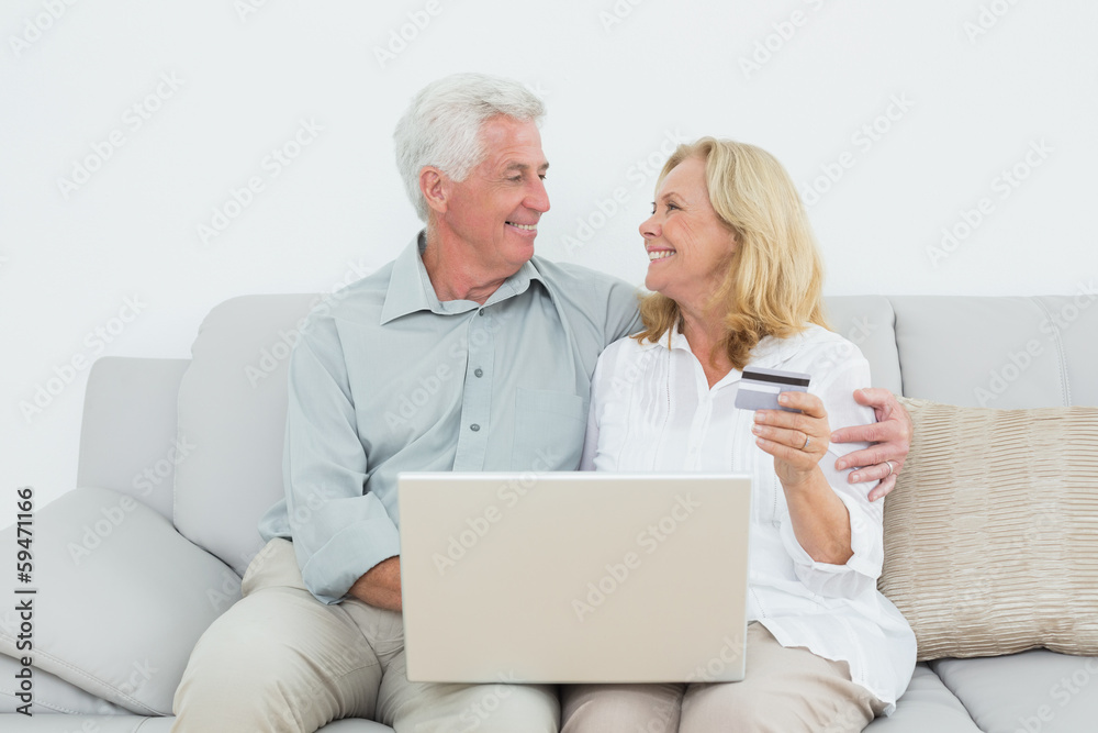 Senior couple doing online shopping on sofa