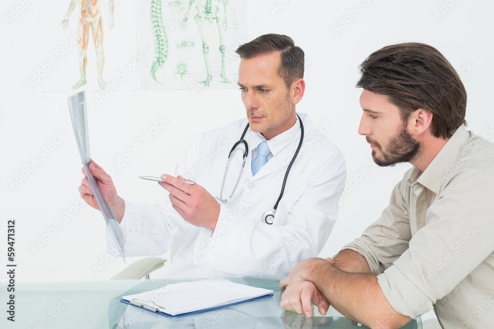 Male doctor explaining spine x-ray to patient Male doctor explaining spine x-ray to patient