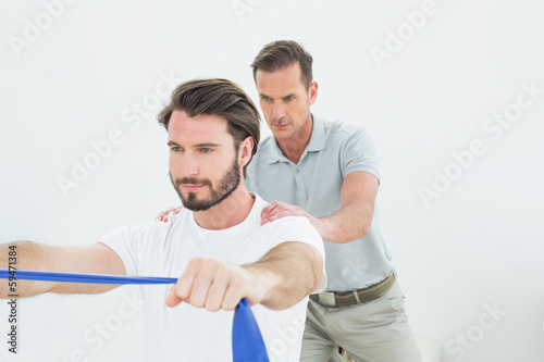 Male therapist assisting a young man with exercises