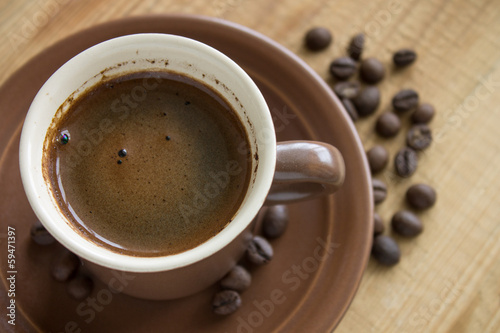 Cup of Coffee with beans on wood background