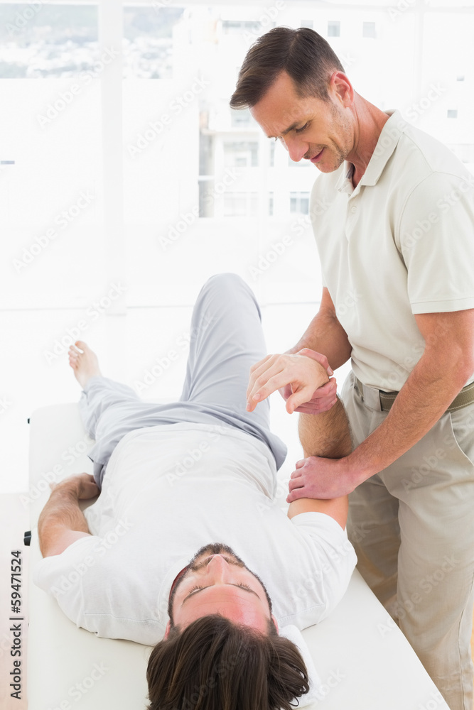 Male physiotherapist examining a man's hand Male physiotherapist examining a man's hand