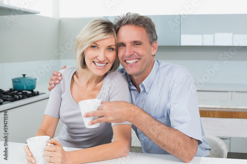 Happy loving couple with coffee cups in kitchen