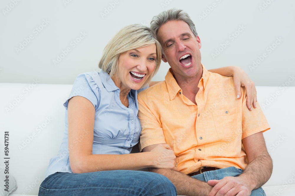 Cheerful couple sitting on sofa at home