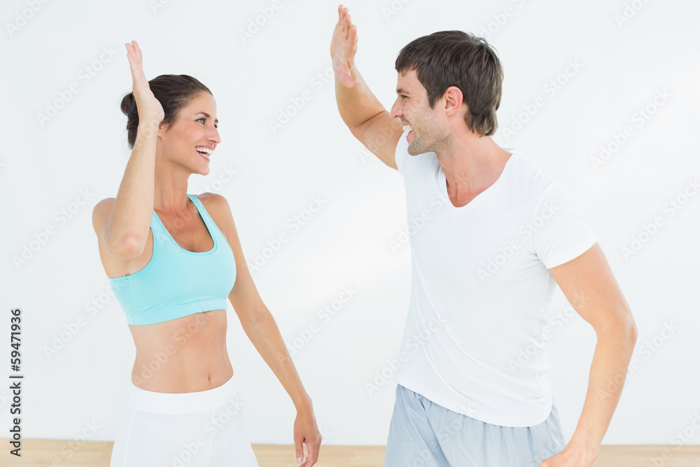 Cheerful fit young couple giving high five