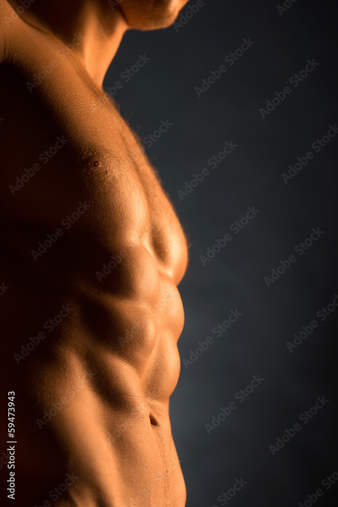 Close up of beautiful muscular male body in golden light