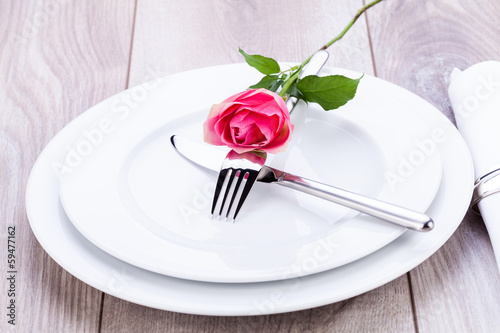romantisch gedeckter tisch mit silberbesteck und einer rose