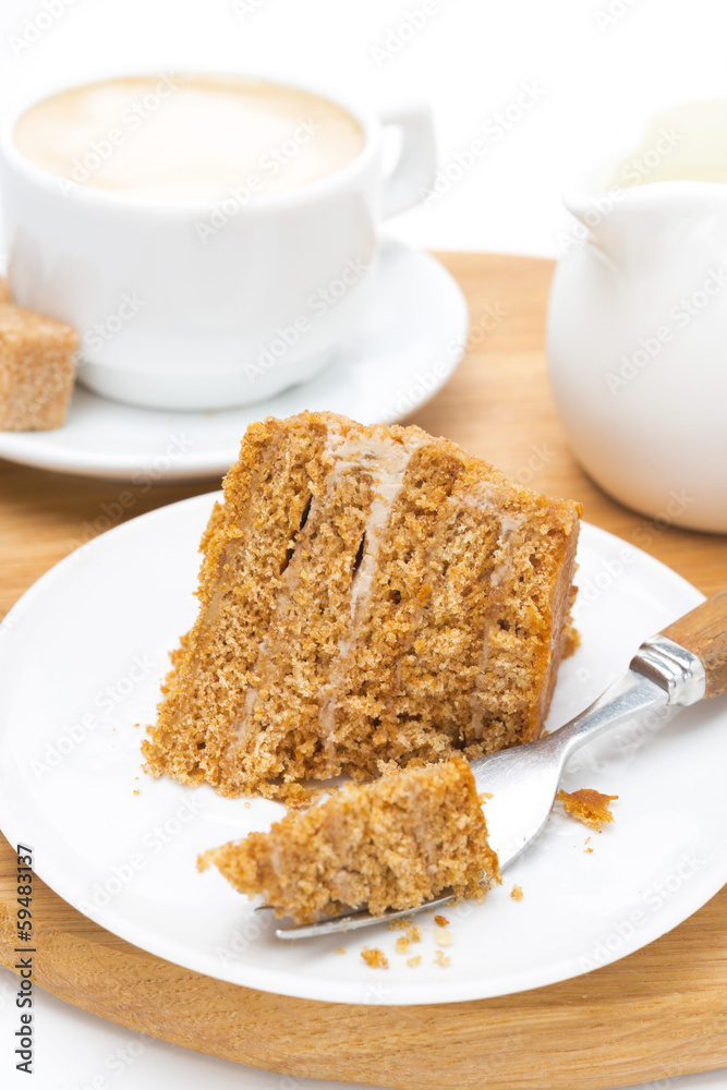 piece of honey cake on a plate, fork and cup of cappuccino piece of honey cake on a plate, fork and cup of cappuccino