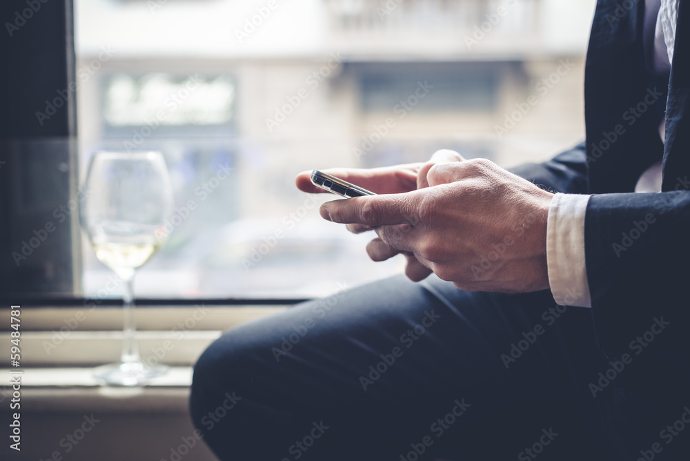 close up of hands typing on cellphone and glass of wine close up of hands typing on cellphone and glass of wine