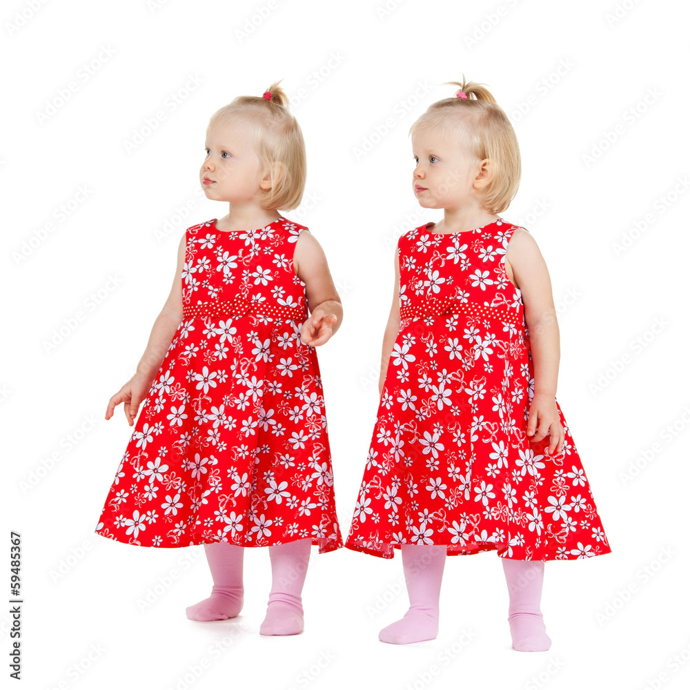 two identical twin girls in red dresses looking two identical twin girls in red dresses looking