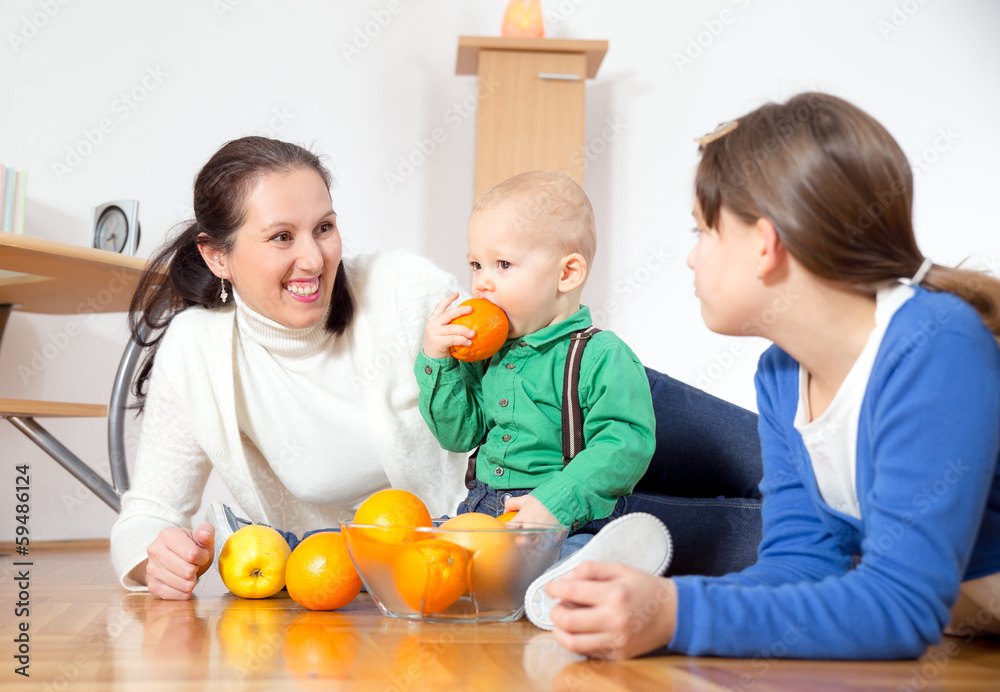 Mother, daughter and baby plays with oranges fruits Mother, daughter and baby plays with oranges fruits