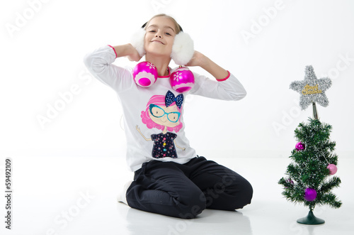 girl holding a Christmas ball with a small Christmas tree