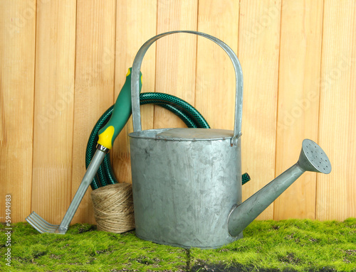 Gardening tools on grass on wooden background