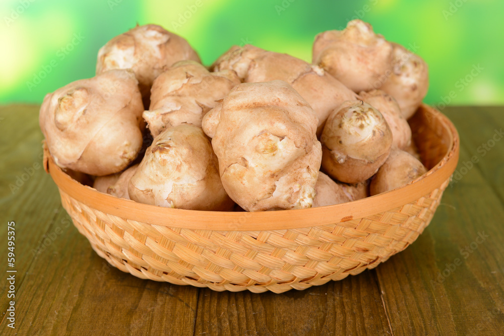 Topinambur roots in wicker basket on table on bright background Topinambur roots in wicker basket on table on bright background