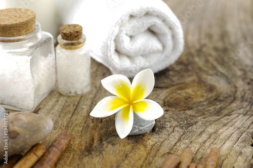 frangipani flower on stone with salt in glass on old wood