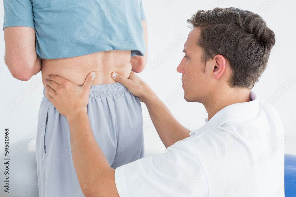 Obraz premium Hands massaging mans lower back in gym hospital