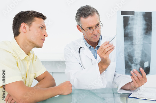 Doctor explaining spine x-ray to patient in office