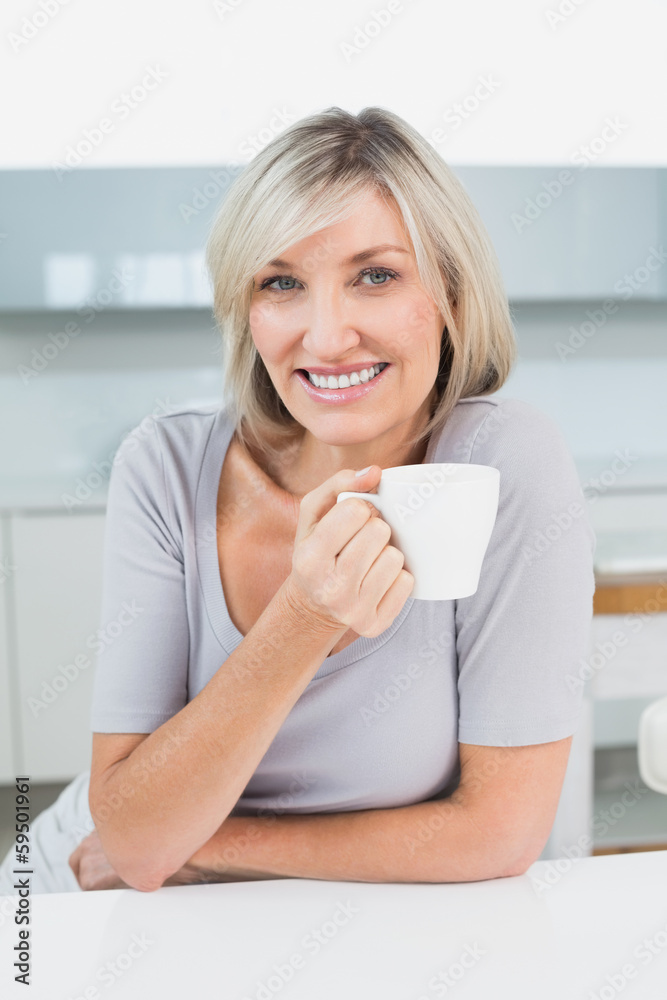 Smiling casual young woman with coffee cup in kitchen Smiling casual young woman with coffee cup in kitchen
