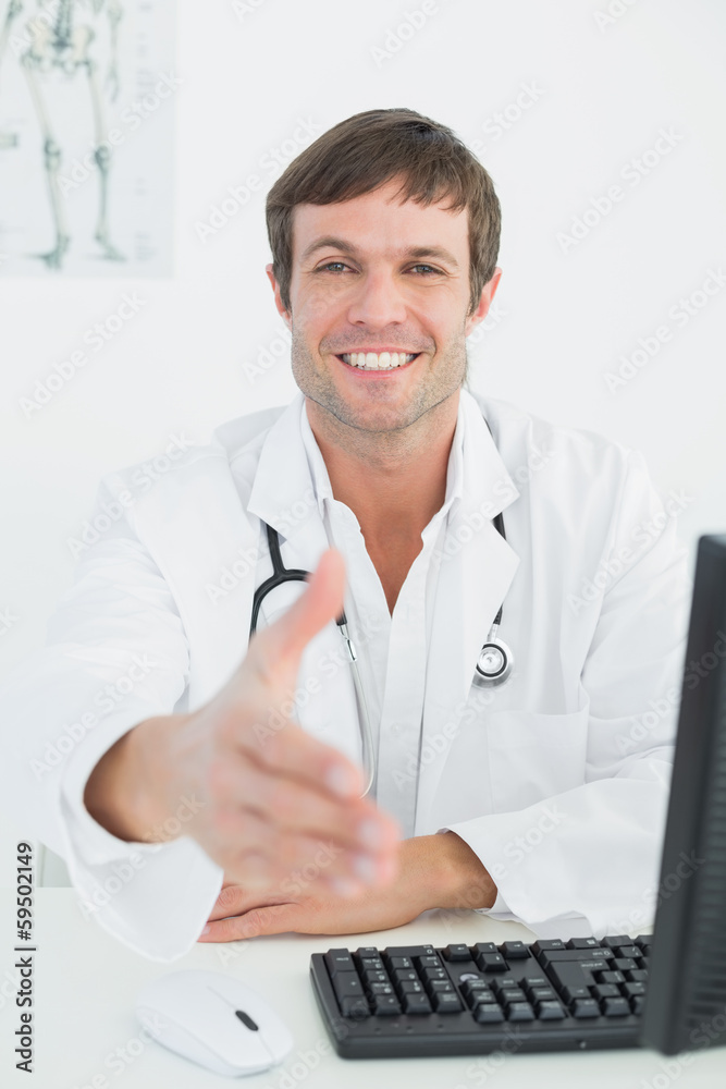 Male doctor offering a handshake at medical office desk Male doctor offering a handshake at medical office desk