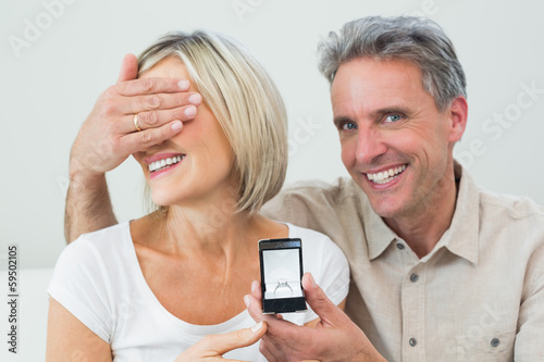 Man covering woman's eyes to offer her an engagement ring