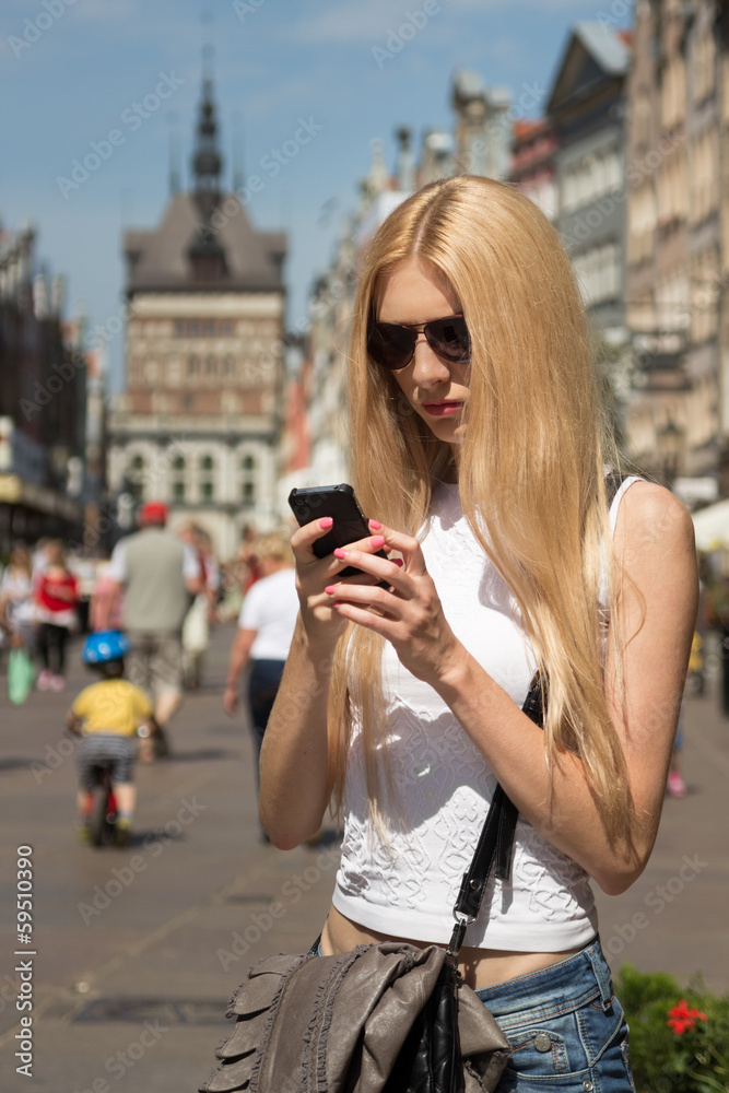 Young woman with phone in hands on the street