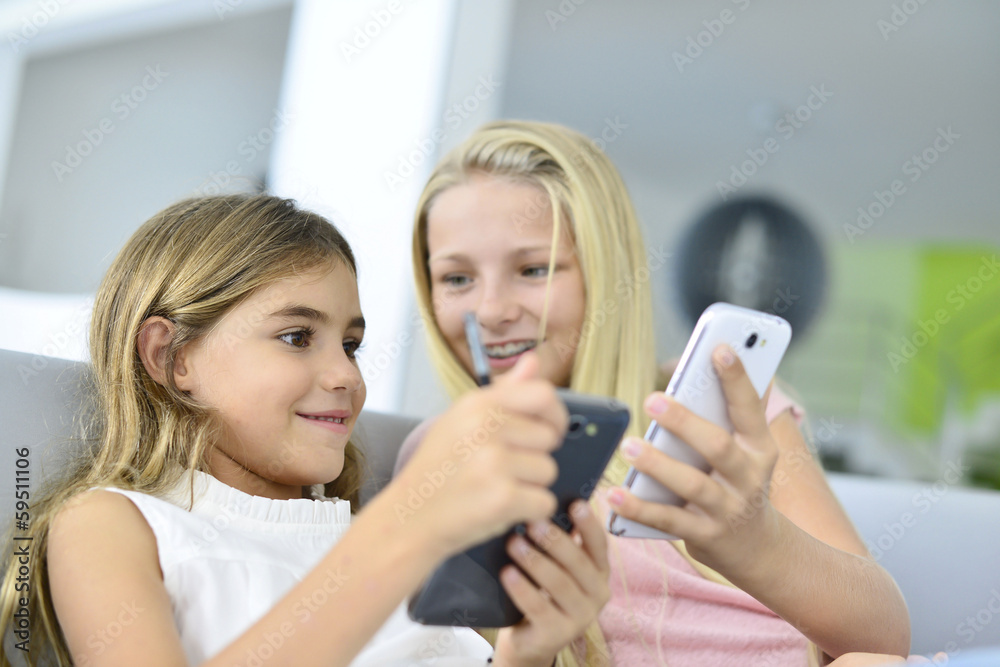 Young girls playing together with smartphone