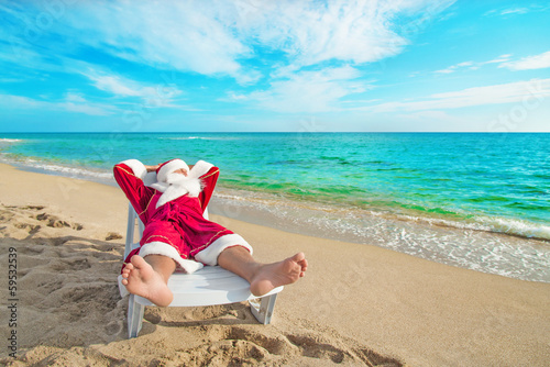 sunbathing Santa Claus relaxing in bedstone on beach - Christmas photo