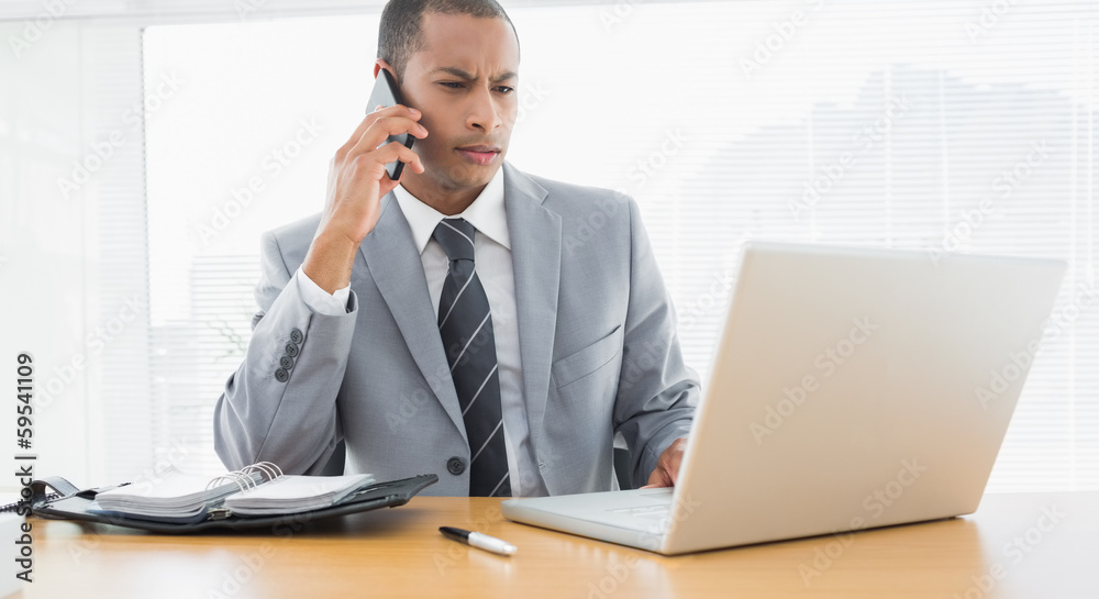 Concentrated businessman using laptop and cellphone Concentrated businessman using laptop and cellphone