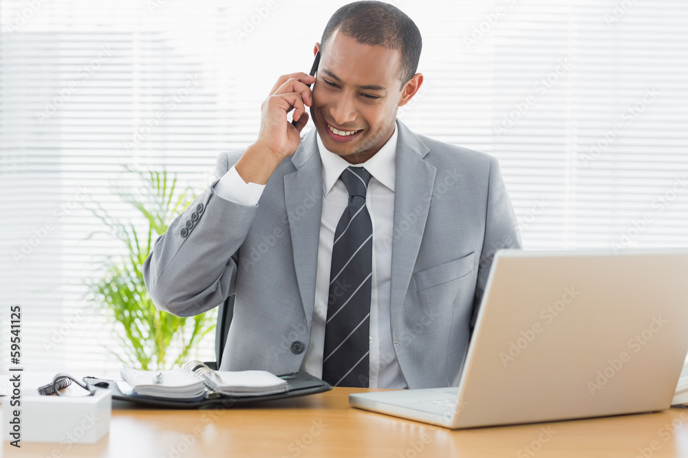 Smiling businessman with laptop using cellphone Smiling businessman with laptop using cellphone