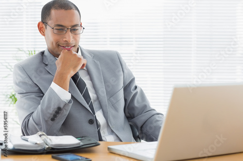 Businessman sitting with laptop at office desk