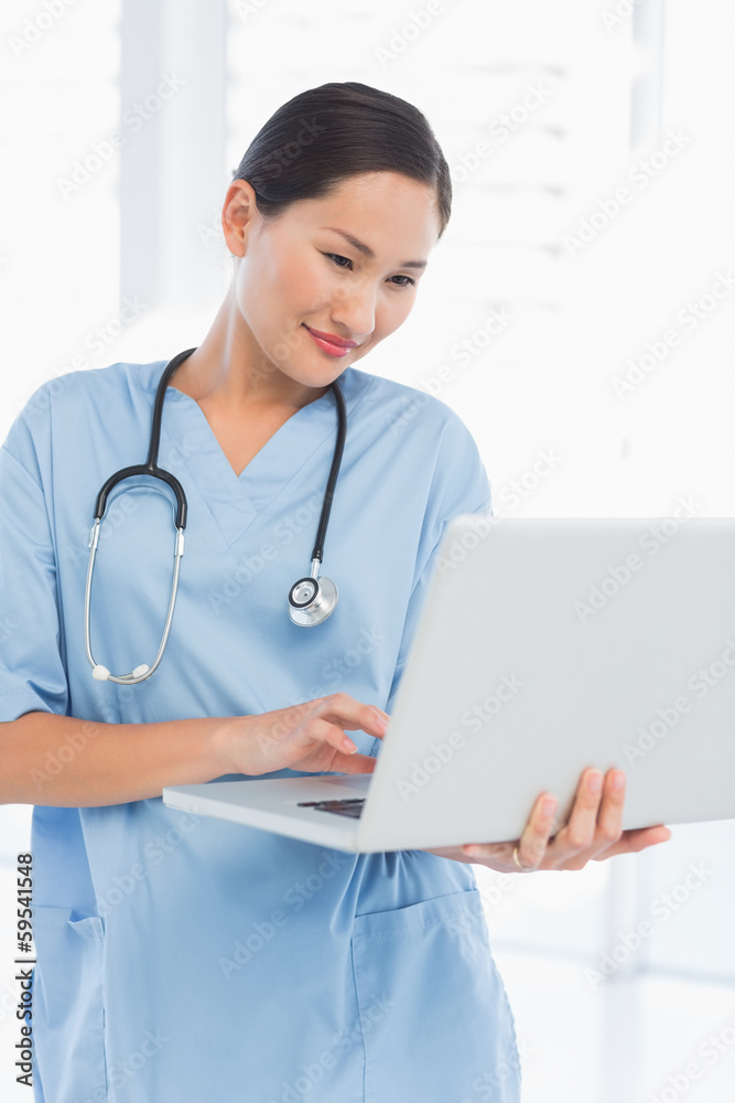 Concentrated female surgeon using a laptop Concentrated female surgeon using a laptop