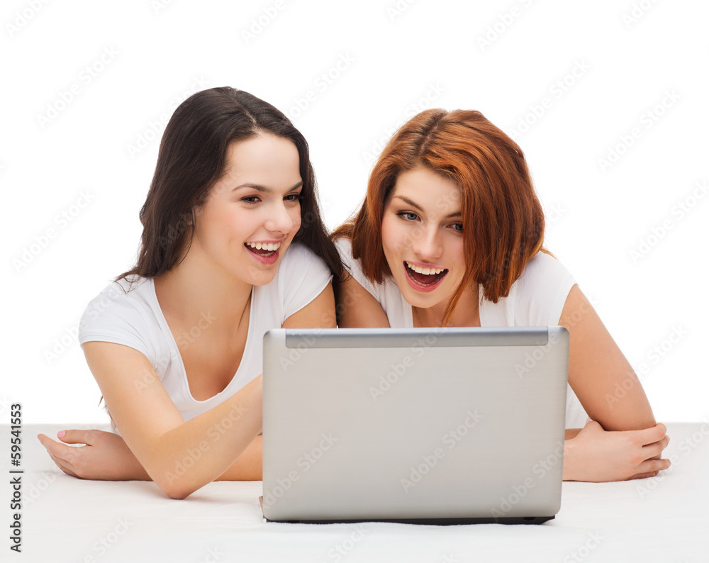 two smiling teenage girsl with laptop computer