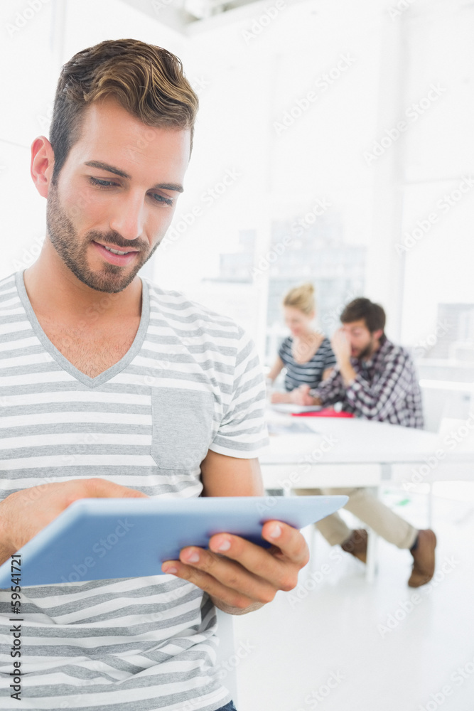 Obraz premium Man using digital tablet with colleagues in background