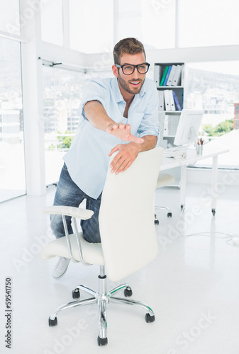 Happy young man kneeling on chair in office