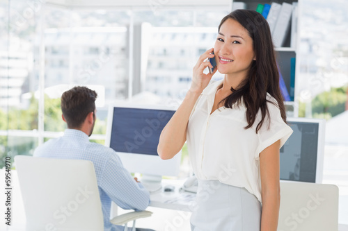 Female artist using mobile phone with colleague in background