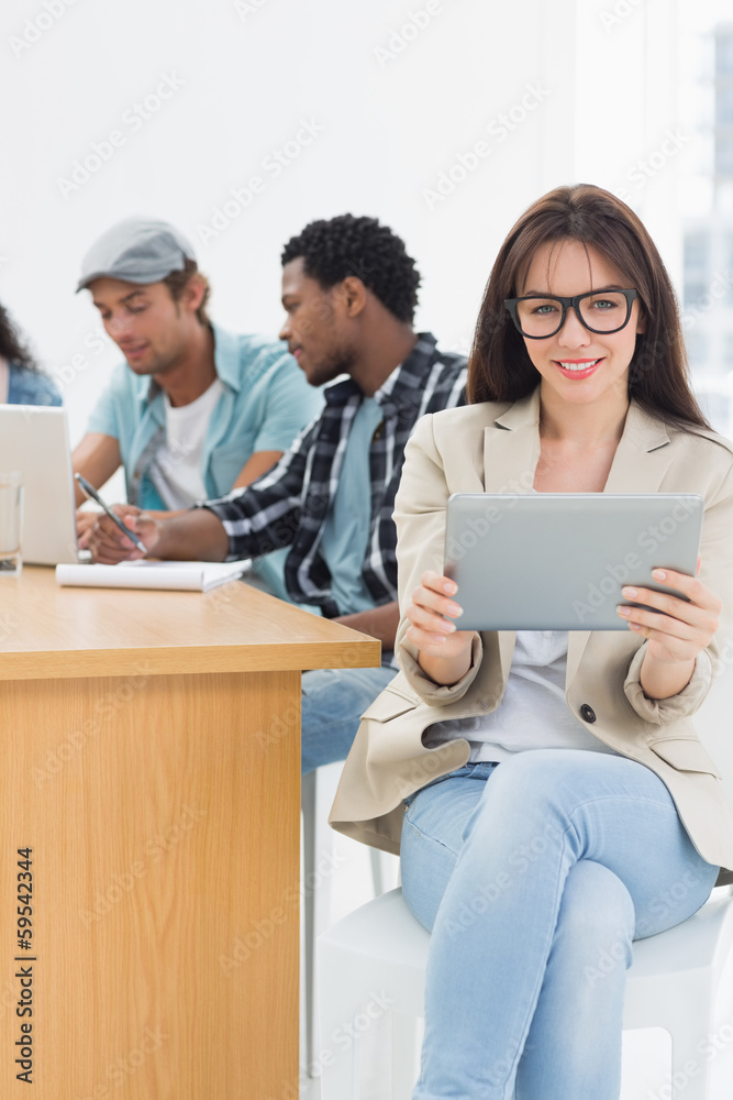 Woman using digital tablet with colleagues behind in office Woman using digital tablet with colleagues behind in office