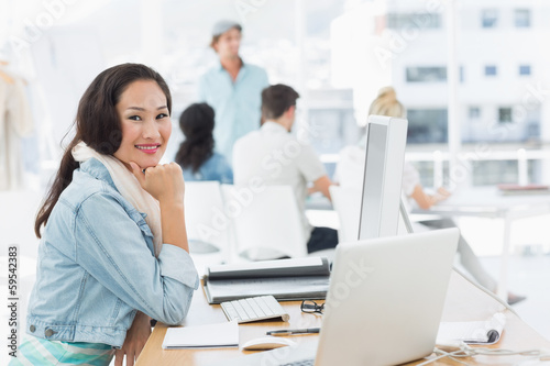 Casual young woman with colleagues behind in office