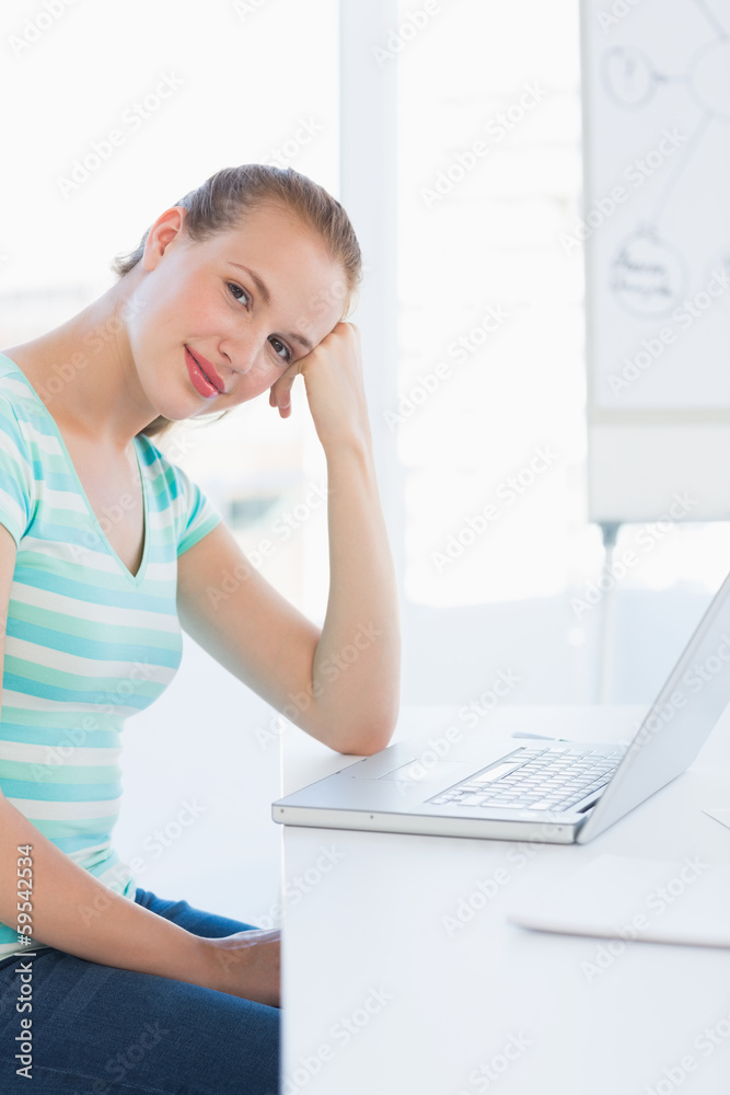 Smiling young casual woman in front of laptop at office Smiling young casual woman in front of laptop at office