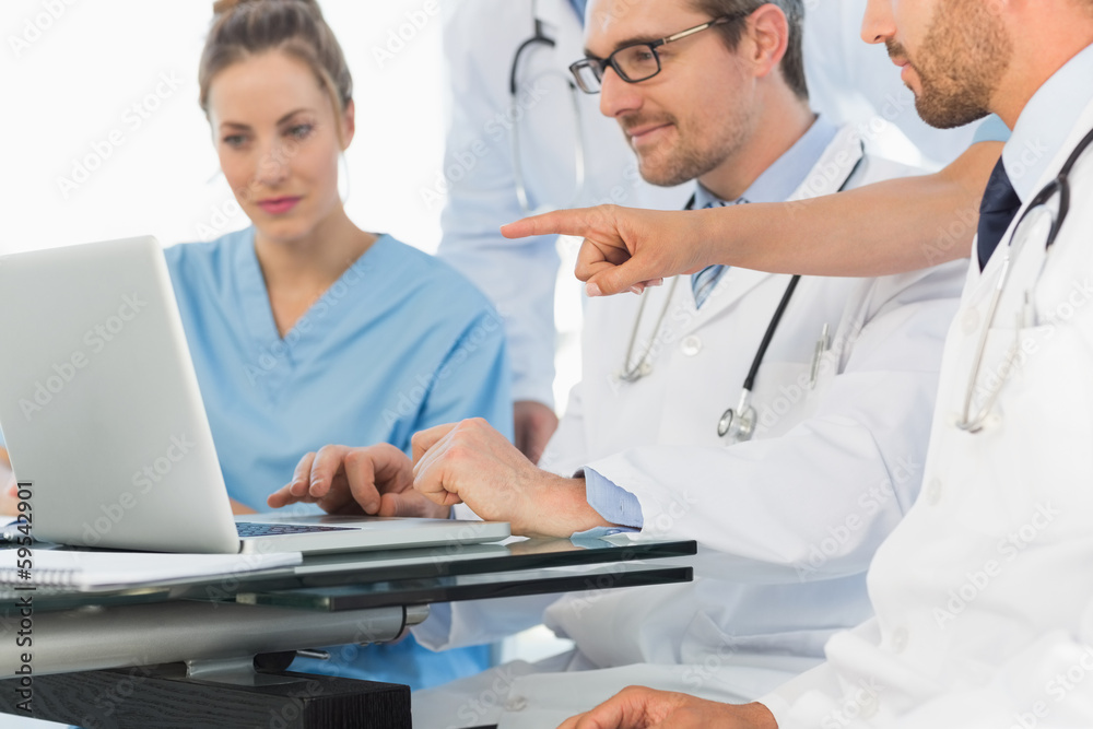 Group of concentrated doctors using laptop together Group of concentrated doctors using laptop together