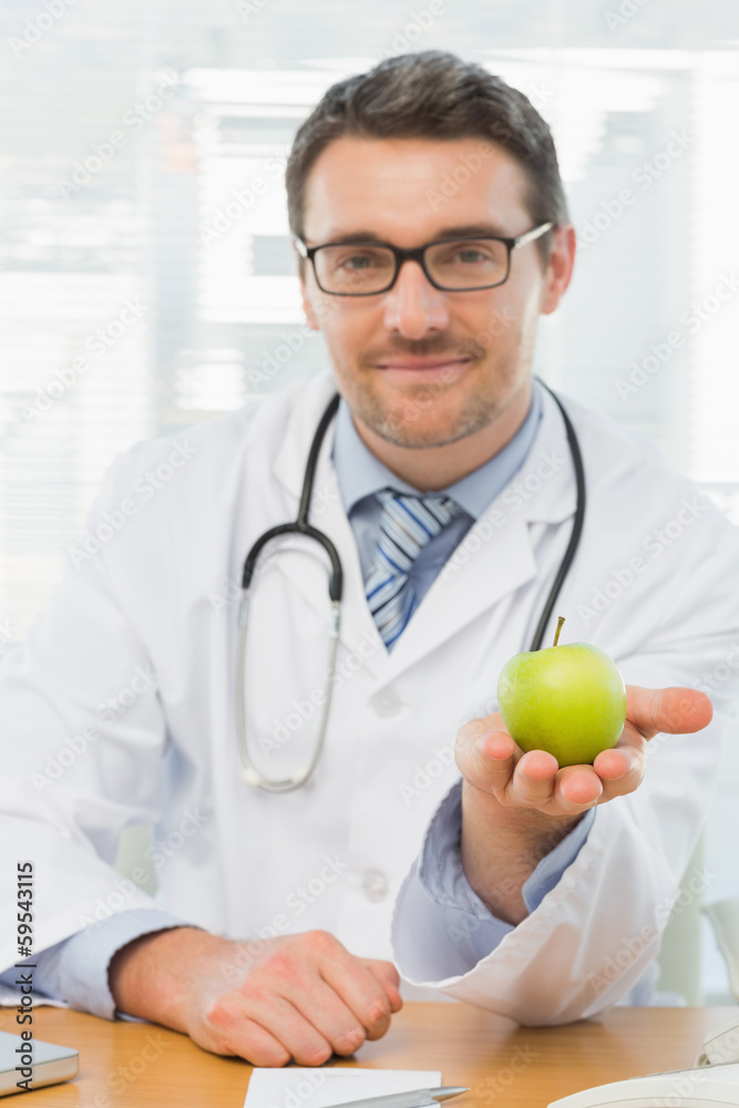 Portrait of a smiling male doctor holding an apple Portrait of a smiling male doctor holding an apple