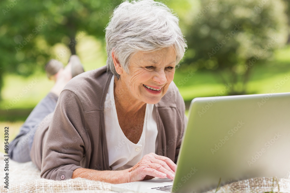 Smiling senior woman using laptop at park Smiling senior woman using laptop at park