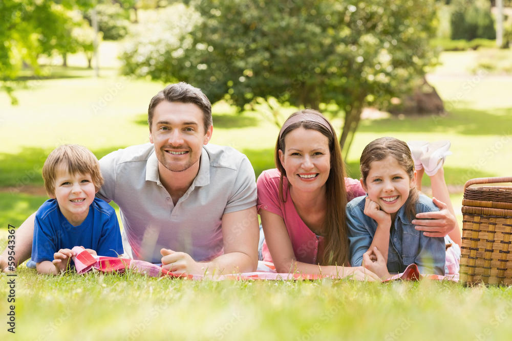 Smiling couple with young kids lying in park