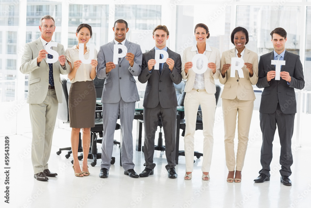 Obraz premium Happy business team holding up letters spelling support