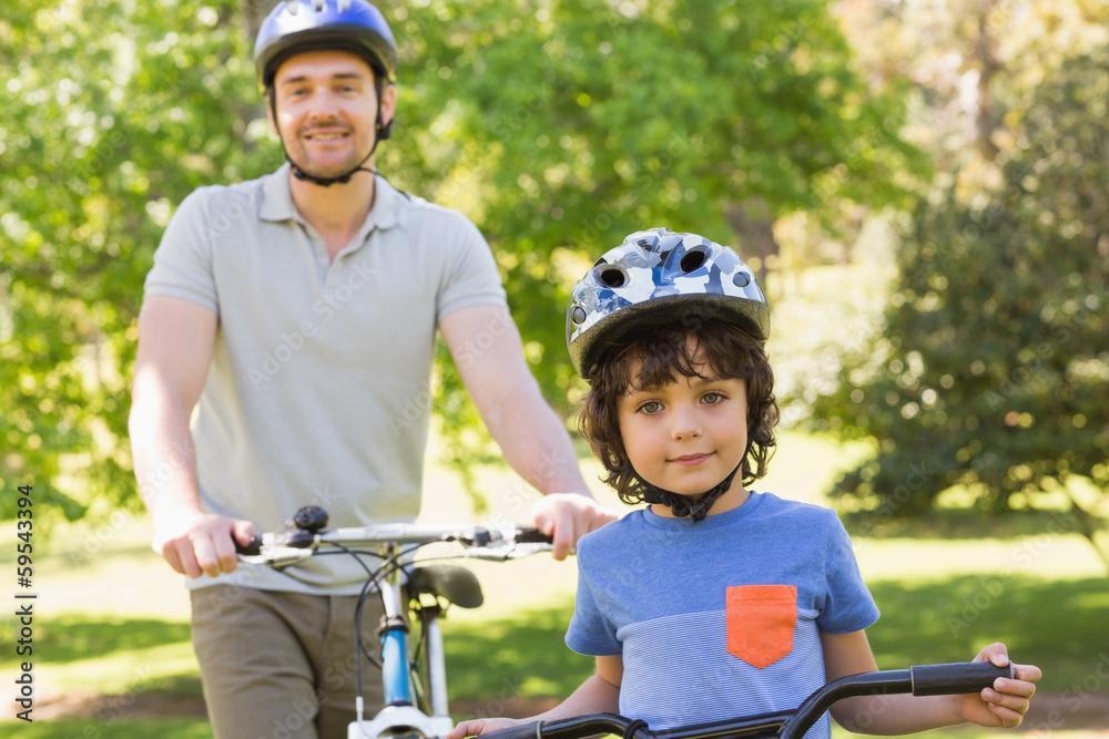 Naklejka premium Smiling man with his son riding bicycles