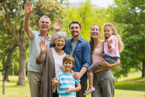Extended family waving hands in park