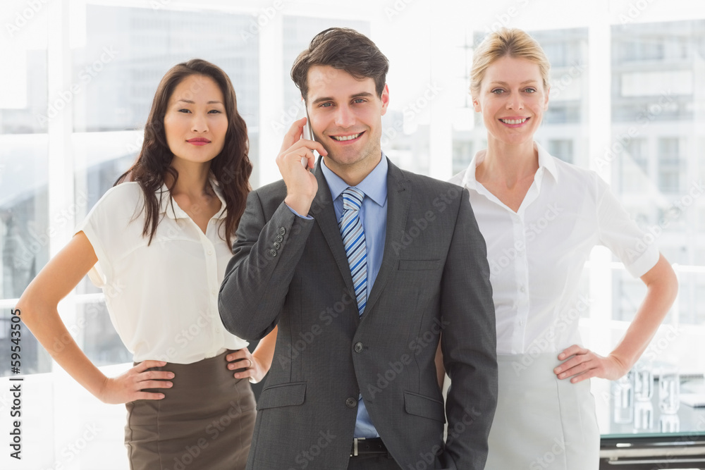 Happy businessman on the phone in front of his team Happy businessman on the phone in front of his team